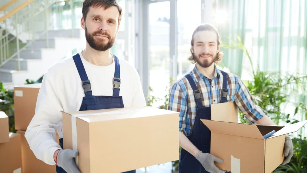 Two smiling movers carrying boxes